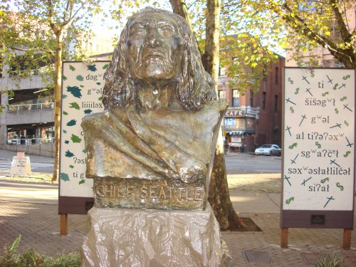 Seattle statue with engravings on stand.